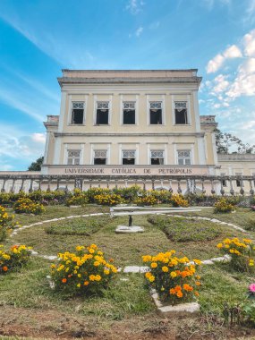 Arkasında Katolik Üniversitesi olan Çiçekli Saat. Petropolis, Rio de Janeiro, Brezilya. 28 Mayıs 2024.