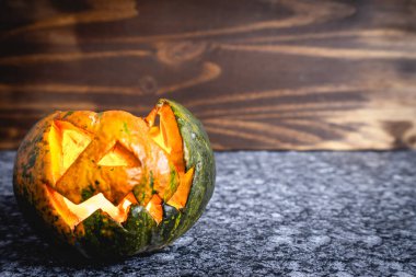 İçinde mum olan küçük bir ev yapımı Cadılar Bayramı kabağı. Karanlık bir arka planda.