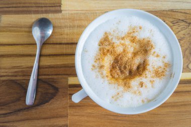 Lezzetli ev yapımı Cappuccino, beyaz bir fincanda, ahşap bir masada. Ev yapımı kahve..