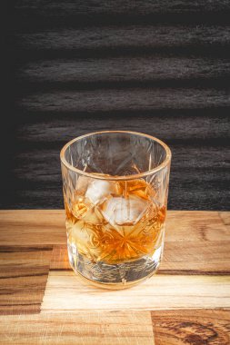 Kayaların üzerinde güzel bir bardak Wiskey, siyah bir arka plan, ve ahşap bir masa..