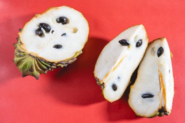 Atemoya, tropikal bir fuit, kırmızı arka planda uzanıyor..