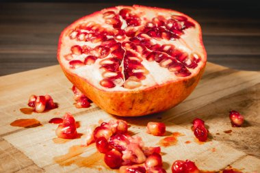 Pomegrenades cut in half on a wooden background. clipart