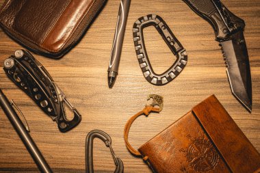 Ahşap bir arka planda siyah ve deri EDC ekipmanı.