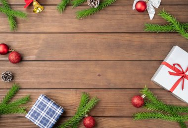 Çam dalları, noel baloları, hediye kutuları ve tahta masa üzerinde fotokopi alanı olan çam kozalakları. Noel süslemesi.