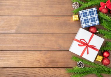 Çam dalları, noel baloları, hediye kutuları ve tahta masa üzerinde fotokopi alanı olan çam kozalakları. Noel süslemesi.