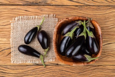 Tahta masanın üzerinde bir kasede küçük bebek patlıcanlar..