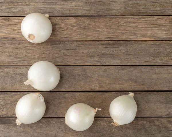 White onions over wooden table with copy space.