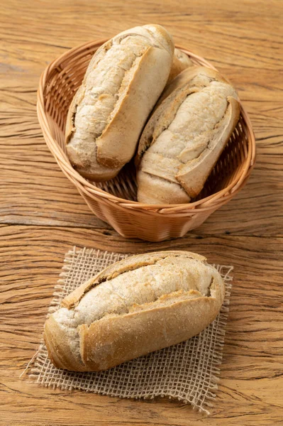 Whole grain french bread, salt bread or pistolet on a basket over wooden table.