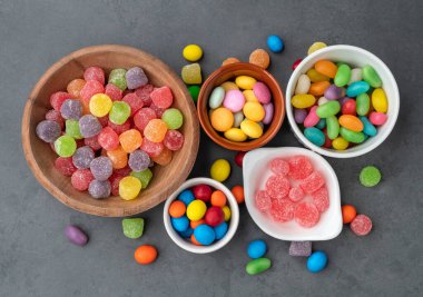 Taş arka planda kâselerde çeşitli renkli şekerler..