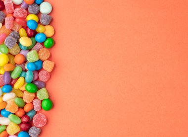 Fotokopi alanı olan turuncu arkaplan üzerindeki renkli şekerler.