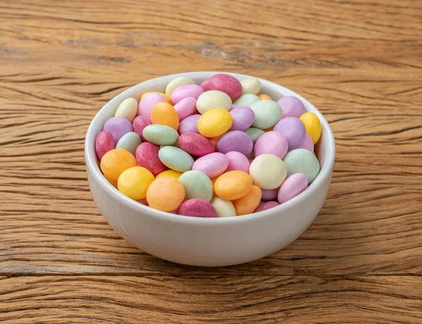 Colorful candies in a bowl over wooden table.