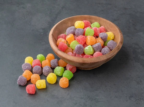 Colorful candies on a bowl over stone background.