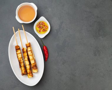 Şekerli bir tabakta ızgara Rennet veya Coalho peyniri ve arkaplanda biber ve fotokopi alanı..