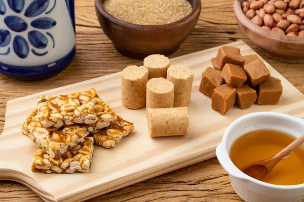 stock image Typical brazilian candies with ingredients over wooden board. Doce de leite or dulce de leche, pe de moleque and pacoca.