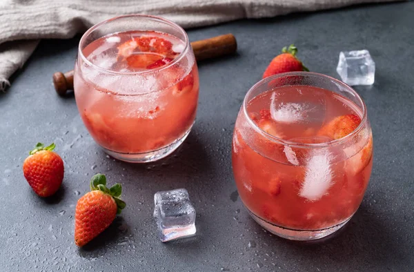 Brazilian strawberry caipirinha in glasses with ice and fruits over stone background.