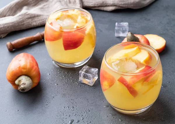 Stock image Brazilian cashew caipirinha in glasses with ice and fruit slices over stone background with copy space.