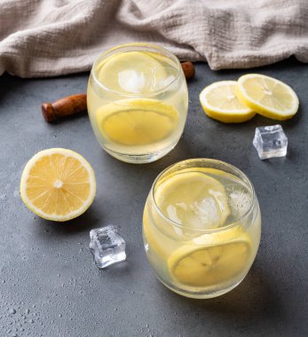 Brazilian sicilian lemon caipirinha in glasses with ice and fruit slices over stone background.