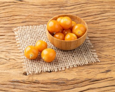 Tahta masanın üzerinde bir kâse üzerinde Physalis..