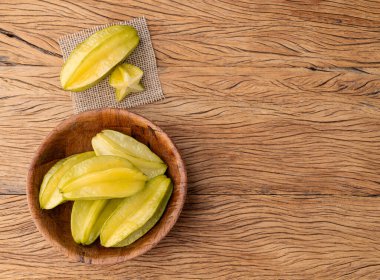 Bir grup yıldız meyvesi, ahşap masa ve fotokopi alanı üzerinde dilimler..