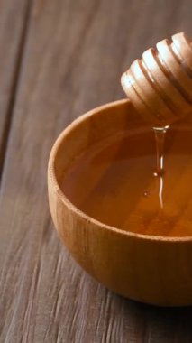 Dikey video. Tahta kepçeli balını bir kaseye atıyor..