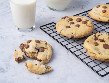 Çikolata parçalı kurabiyeler mermer masanın üzerinde sütle..