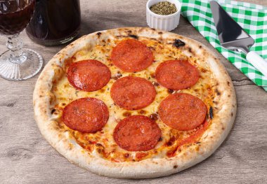 Biberli sosis stili pizza ahşap masa üzerinde şarap, kekik otu ve spatula..