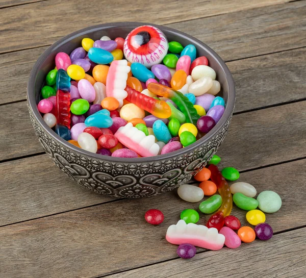 Assorted colorful candies on a bowl over wooden table.