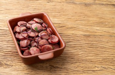 Grilled calabrese sausage portion with onion over wooden table with copy space.