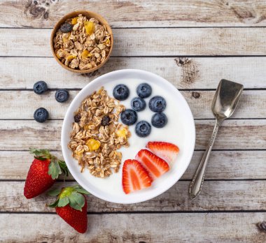 Çilekli yoğurt, yaban mersini ve tahıl gevreği ahşap bir masada..