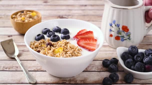酸奶与草莓 蓝莓和格拉诺拉 倒蜂蜜在碗在木制桌子上 — 图库视频影像