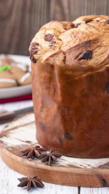 Dikey video. Geleneksel İtalyan pastası panettone üzerinde çikolata parçacıkları beyaz ahşap masa.