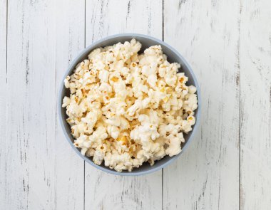 Tahta masanın üzerinde kasede patlamış mısır..