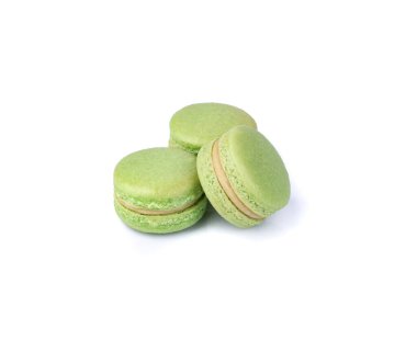 Beyaz arka planda üç tane fıstıklı badem kurabiyesi var..