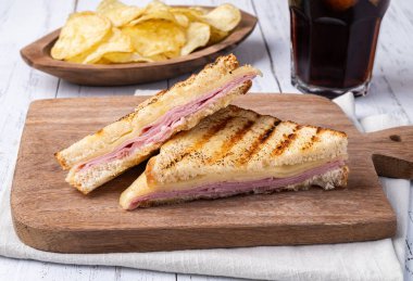 Peynirli ve jambonlu sandviç, patates cipsi ve soda..