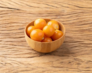 Tahta masanın üzerinde bir kâse üzerinde Physalis..