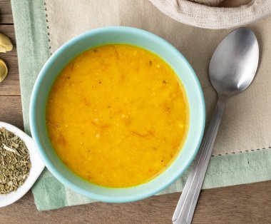 Balkabağı ve kurutulmuş et çorbası ekmek dilimleri ve ahşap masa üzerinde çeşnili..