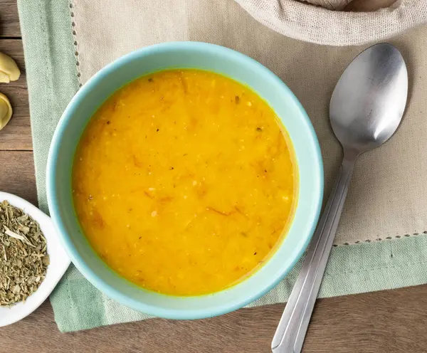 Balkabağı ve kurutulmuş et çorbası ekmek dilimleri ve ahşap masa üzerinde çeşnili..