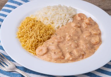 Pirinçli karides strogonoff ve ahşap masanın üzerinde saman patates..