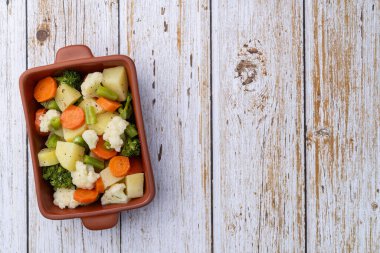 Ahşap bir masanın üzerinde, fotokopi alanı olan bir tabakta pişirilmiş sebze..