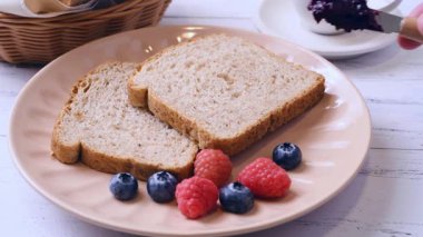 Böğürtlenli ekmeğe reçel sürüyorum.