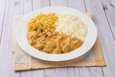 Pirinçli et strogonoff ve ahşap masanın üzerinde saman patates..