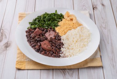 Pirinç, biber, farofa, lahana ve çıtırtılı tipik Brezilya feijoadası..