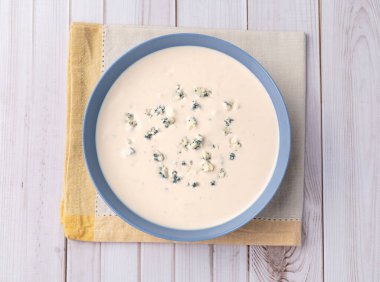 Tahta masanın üzerinde bir kasede peynir çorbası..