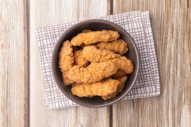 Ahşap bir masanın üzerinde tavuk ısırıkları..