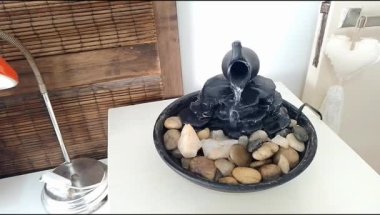 Beyaz ahşap bir masanın tepesindeki dekoratif zen çeşmesinin yakın görüntüsü