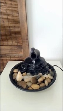 Close view of a decorative zen water fountain on top of a white wooden table