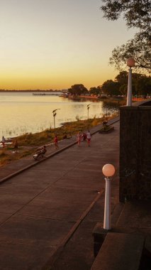        Chascomus, Buenos Aires, Arjantin. 2-2-2025. İnsanlar yaz öğleden sonra Chascomus Gölü 'nün yanında yürüyüş yapıyorlar.                                       