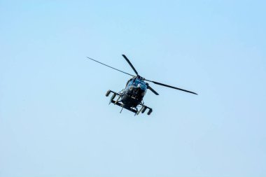 Combat helicopter is flying against isolated blue sky. Combat helicopter attack enemy.