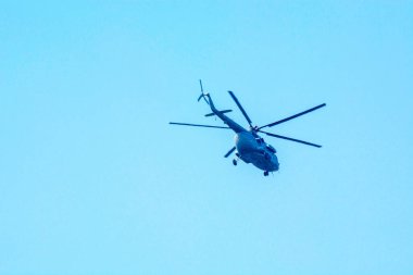 Combat helicopter is flying against isolated blue sky. Combat helicopter attack enemy.