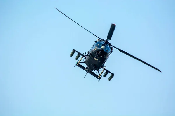 Close-up of combat helicopter is flying against isolated blue sky.